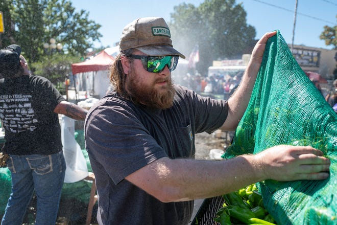 Chance Adair adds a bushel of Pueblo chiles to a roaster during the 28th Annual Chile and Frijoles Festival on Saturday, Sept. 24, 2022.