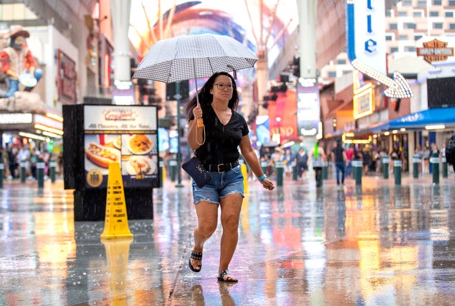 A woman runs through the rain on Fremont Street in downtown Las Vegas, Saturday, Aug. 19, 2023. As Hurricane Hilary approaches, Nevada Gov. Joe Lombardo activated 100 National Guard troops to Southern Nevada, late Friday.