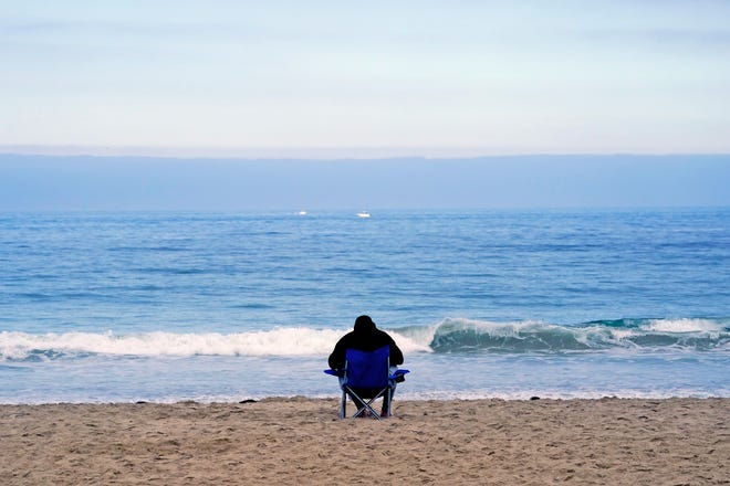 A beachgoer sits in the calm ahead of an approaching Hurricane Hilary, at San Diego's Mission Beach, Saturday, Aug. 19, 2023.