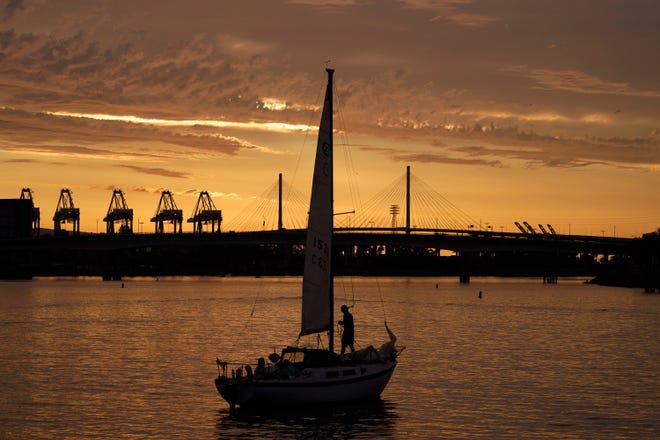A sailboat prepares to dock as the sun sets over the Long Beach International Gateway ahead of Hurricane Hilary in Long Beach, Calif., Saturday, Aug. 19, 2023.
