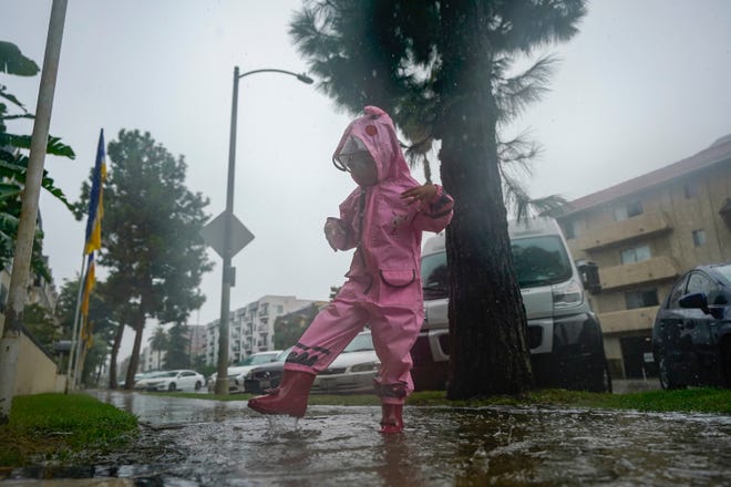 A child plays in the rain, Sunday, Aug. 20, 2023, in Los Angeles.