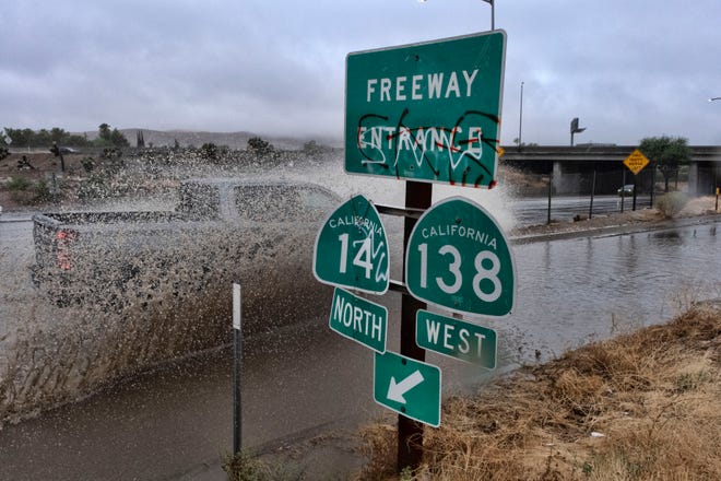 A vehicle engulfed in water drives through a flooded freeway entrance in Palmdale, Calif. as a tropical storm moves into the area on Sunday, Aug. 20, 2023.