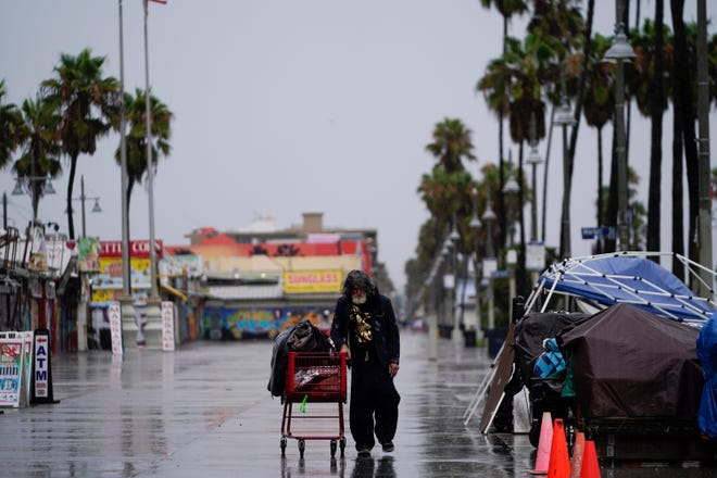 A man walks past empty vendor stands on Venice Beach, Sunday, Aug. 20, 2023, in Los Angeles.