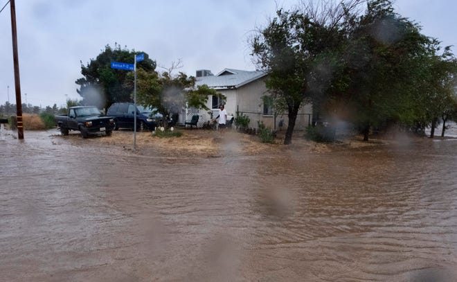A resident checks the floodwaters surrounding his home during a downpour in Palmdale, Calif., as Tropical Storm Hilary moves into the area on Sunday, Aug. 20, 2023. (