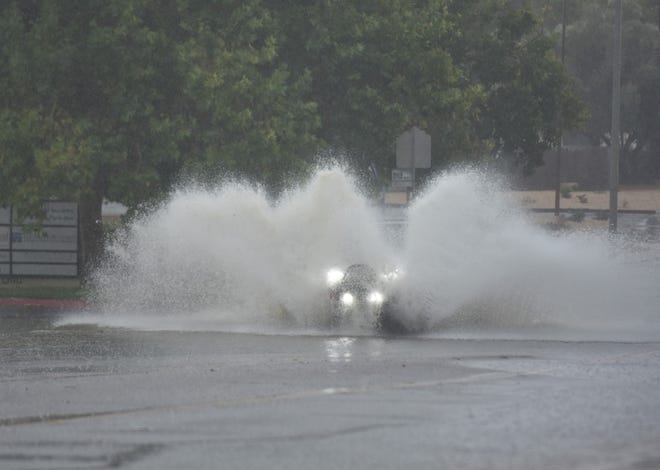 A vehicle splashes up water during heavy rains from Hurricane Hilary, on Park Avenue, in Victorville, California, on August 20, 2023. Hurricane Hilary weakened to a tropical storm but was still likely to bring flooding to the region.